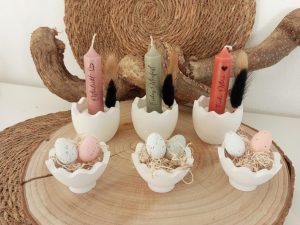 Osterdekoration mit Kerzen und Eiern auf rustikalem Holztablett