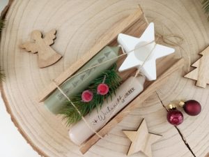 Weihnachtliche Geschenkverpackung mit Kerzen und Holzdekoration auf Baumscheibe